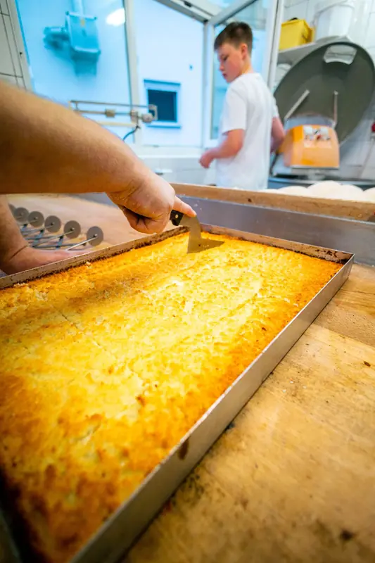 Frischer Blechkuchen wird in der Backstube geschnitten