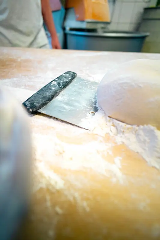 Teigling und Teigschaber auf dem bemehlten Holztisch